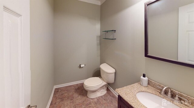 bathroom with toilet, vanity, and crown molding