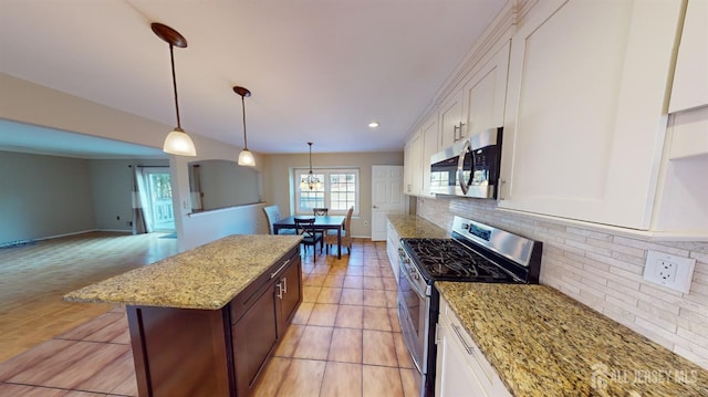 kitchen featuring light stone counters, appliances with stainless steel finishes, pendant lighting, and white cabinetry