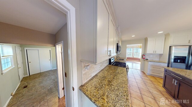 kitchen with stainless steel appliances, light stone countertops, light tile patterned floors, decorative backsplash, and white cabinets