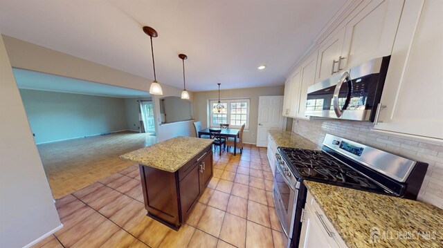 kitchen featuring stainless steel appliances, white cabinetry, hanging light fixtures, and light stone counters