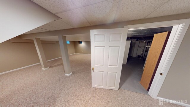 basement with a paneled ceiling and light carpet