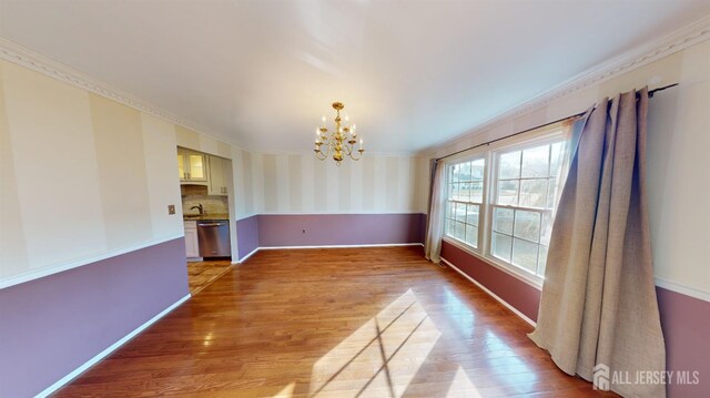 unfurnished dining area featuring ornamental molding, an inviting chandelier, and light wood-type flooring