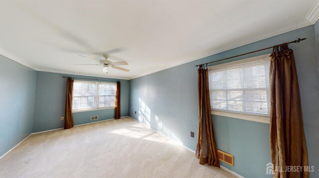 unfurnished room with ceiling fan, crown molding, and light carpet