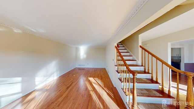 staircase with ornamental molding and wood-type flooring