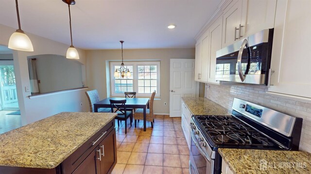 kitchen with stainless steel appliances, white cabinets, and pendant lighting