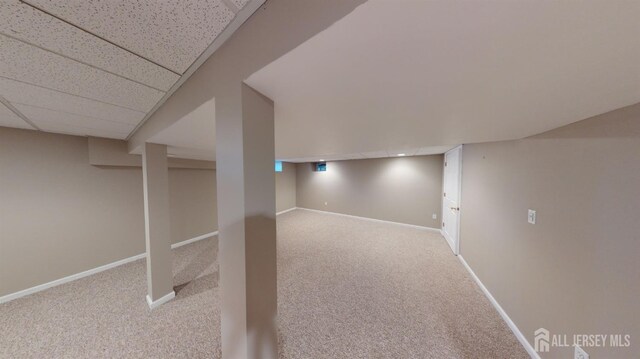 basement with a paneled ceiling and carpet