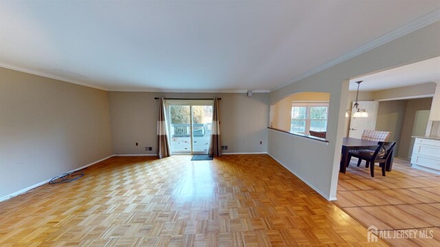 empty room with a notable chandelier, a healthy amount of sunlight, and ornamental molding