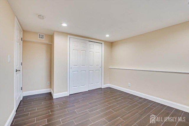 unfurnished bedroom with visible vents, baseboards, a closet, and wood finish floors