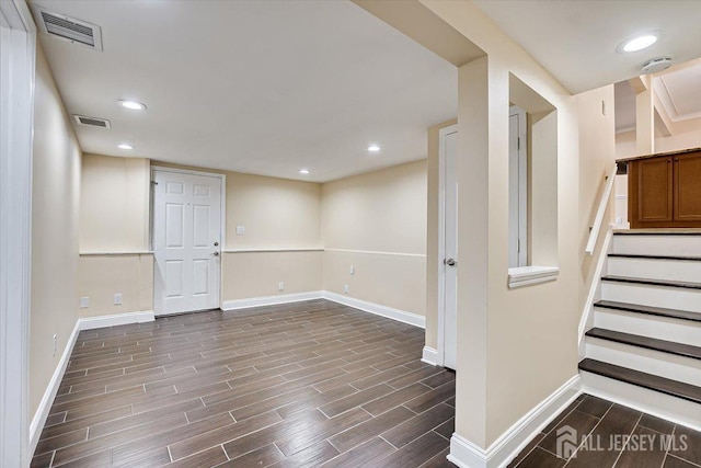 below grade area with wood finish floors, visible vents, baseboards, and stairs