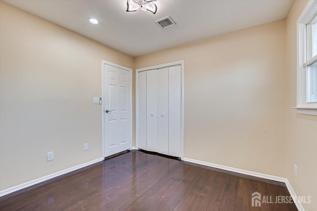 spare room with visible vents, baseboards, and dark wood-style flooring