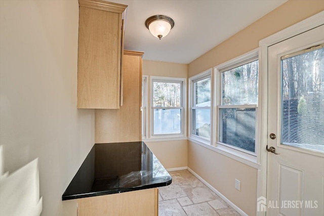 4 Adelphi Ct, Edison, NJ 08837 - kitchen featuring stone tile floors, baseboards, dark countertops, light brown cabinets, and healthy amount of natural light