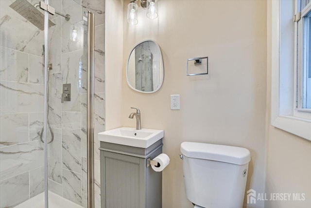 full bath with vanity, toilet, and a marble finish shower