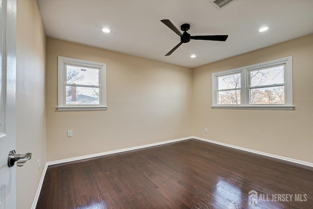 spare room featuring dark wood finished floors, recessed lighting, a healthy amount of sunlight, and baseboards