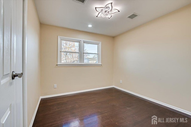 empty room with dark wood-type flooring, baseboards, and visible vents