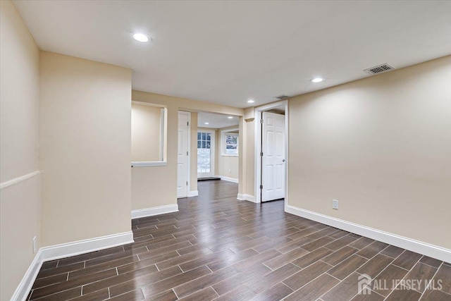 empty room with dark wood-type flooring, recessed lighting, and baseboards