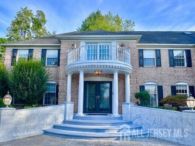 view of front of home with french doors and a balcony