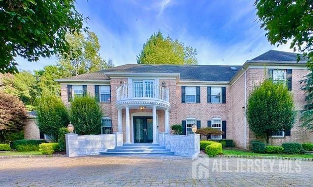 colonial inspired home featuring a balcony and french doors