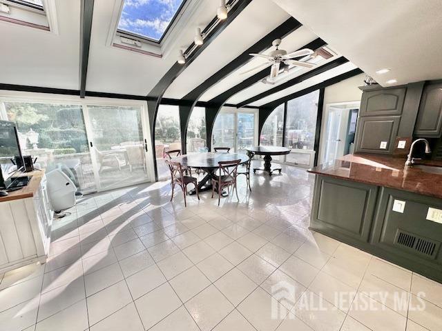 sunroom / solarium featuring lofted ceiling with beams, ceiling fan, and sink