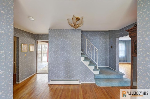 stairs featuring baseboards, baseboard heating, hardwood / wood-style floors, and wallpapered walls