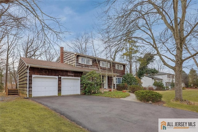 view of front of property with aphalt driveway, roof with shingles, a front yard, a garage, and a chimney