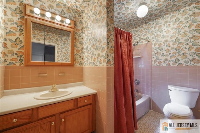 full bathroom with a wainscoted wall, toilet, vanity, and wallpapered walls