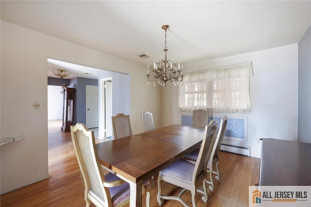 dining space with visible vents, hardwood / wood-style flooring, a baseboard radiator, baseboards, and a chandelier