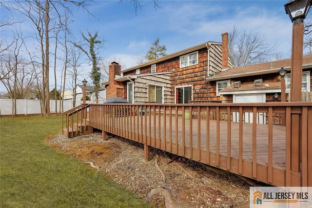 wooden terrace featuring a yard and fence