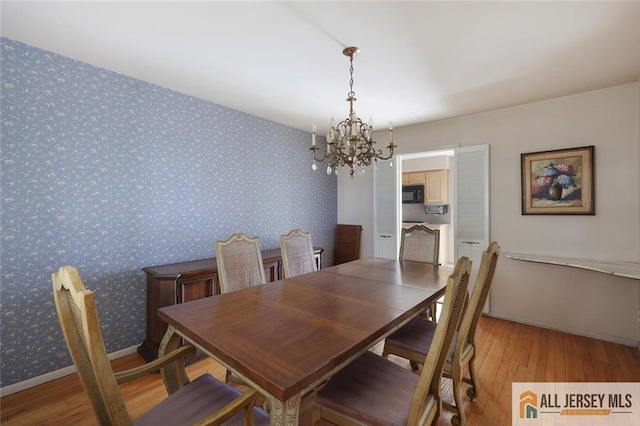 dining area with baseboards, light wood finished floors, an inviting chandelier, and wallpapered walls