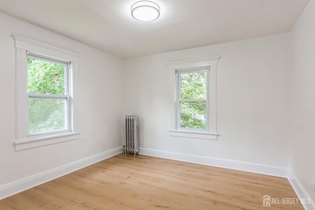 345 1st St, Dunellen, NJ 08812 - unfurnished room featuring radiator heating unit, plenty of natural light, light wood-style floors, and baseboards