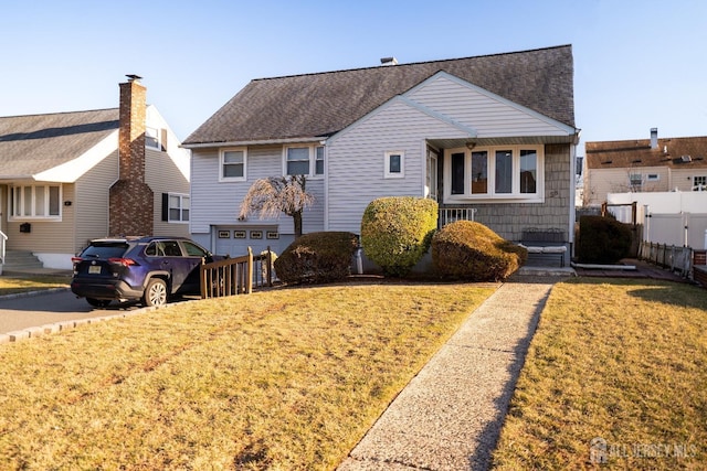 view of front of home featuring a garage, roof with shingles, a front yard, and fence