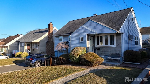 view of front of house with a front yard, roof with shingles, a residential view, and a chimney