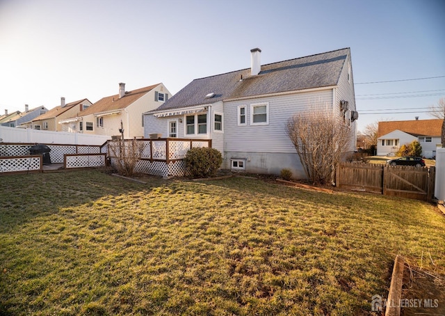 rear view of house with a residential view, fence, a lawn, and a wooden deck