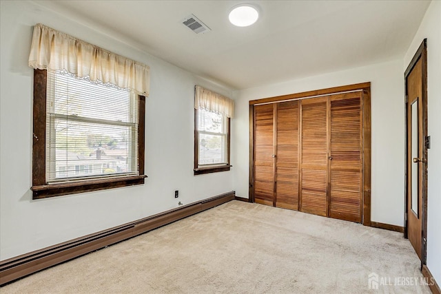 unfurnished bedroom featuring carpet floors, multiple windows, baseboard heating, and visible vents