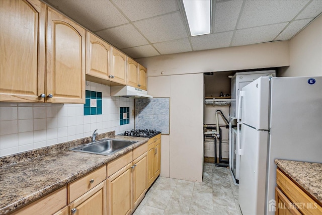 kitchen with light brown cabinetry, a sink, black gas cooktop, freestanding refrigerator, and tasteful backsplash