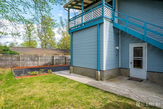 view of home's exterior with fence, a lawn, and a balcony