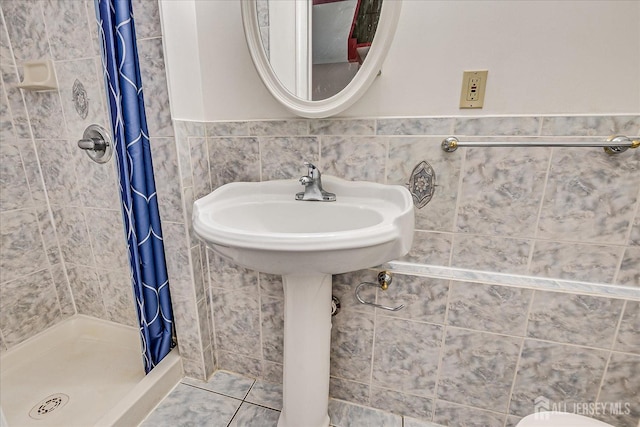 full bath featuring tile walls and a shower stall