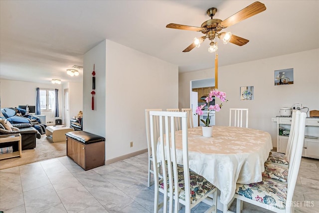 dining space with a ceiling fan and marble finish floor