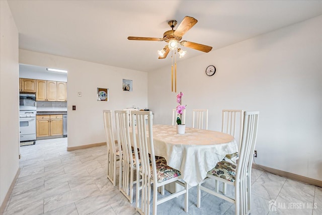 dining area featuring a ceiling fan, baseboards, and marble finish floor