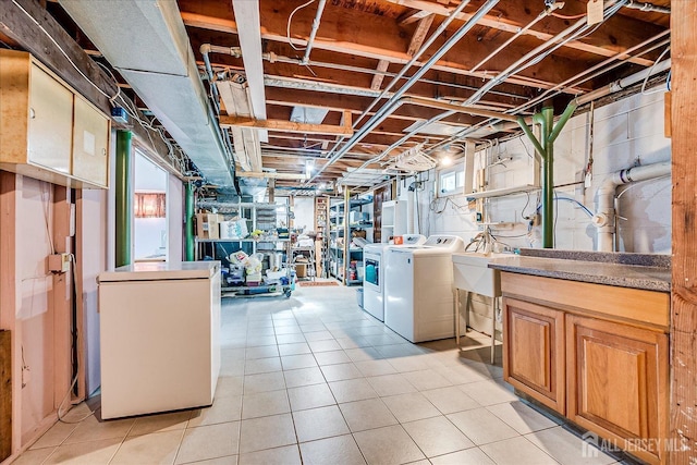 basement featuring independent washer and dryer, fridge, a sink, and light tile patterned floors