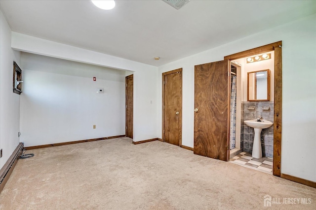 unfurnished bedroom featuring carpet flooring, baseboards, multiple closets, and a sink