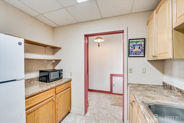 kitchen featuring a paneled ceiling, black microwave, light brown cabinetry, open shelves, and freestanding refrigerator