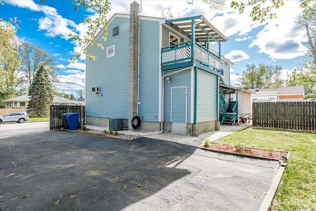 back of house with fence, a balcony, a chimney, and entry steps