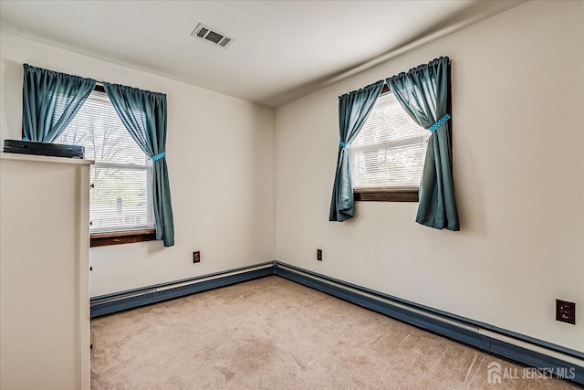 spare room with carpet floors, plenty of natural light, baseboards, and visible vents