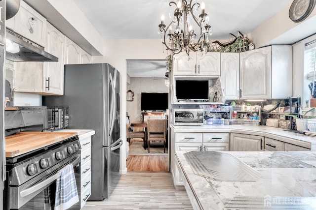 24 Higgins Rd, Old Bridge, NJ 08857 - kitchen with stainless steel appliances, a chandelier, light wood-type flooring, pendant lighting, and white cabinetry