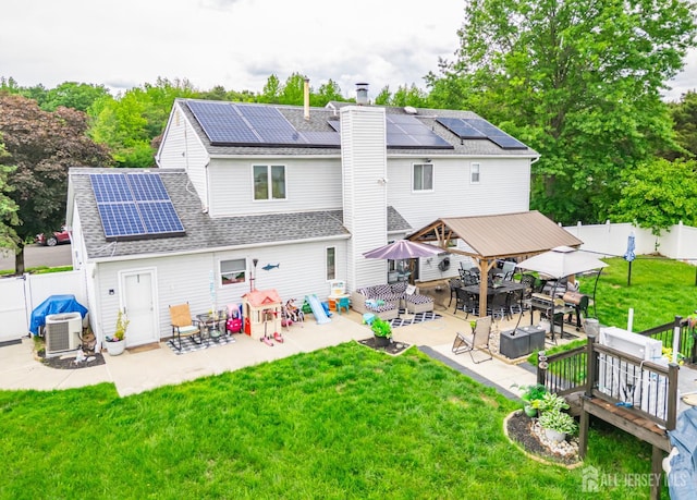 24 Higgins Rd, Old Bridge, NJ 08857 - rear view of house featuring roof mounted solar panels, a patio, a chimney, and a shingled roof