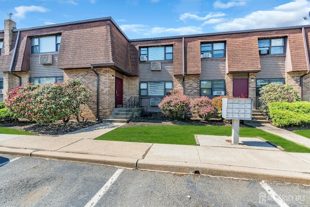 1133 Livingston Ave Unit 11C, North Brunswick, NJ 08902 - view of property featuring brick siding, uncovered parking, and mansard roof