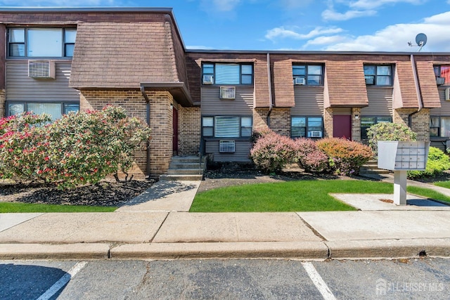 1133 Livingston Ave Unit 11C, North Brunswick, NJ 08902 - view of property featuring uncovered parking, brick siding, and mansard roof