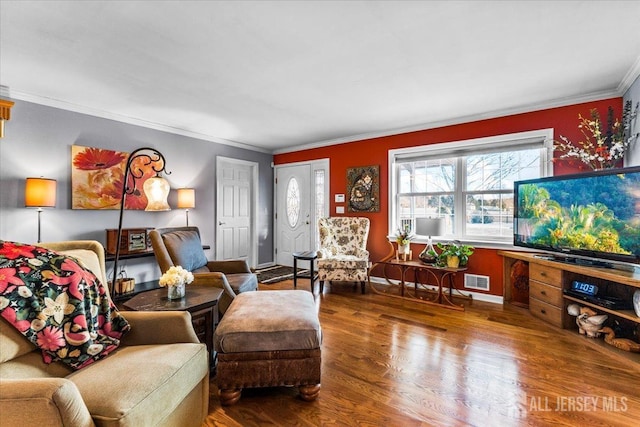 living room with baseboards, wood finished floors, visible vents, and crown molding