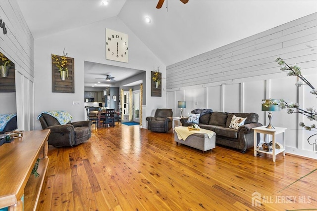 living area with a ceiling fan, high vaulted ceiling, and hardwood / wood-style flooring
