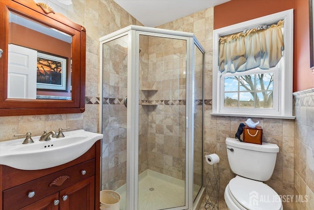 bathroom featuring toilet, a stall shower, vanity, and tile walls